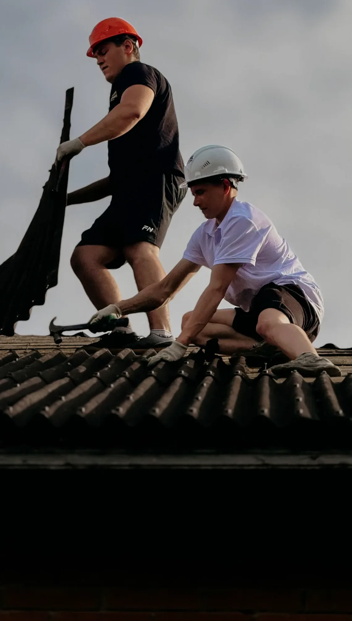 Dues persones treballant sobre un vessant de teula